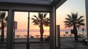 Zonsondergang uitzicht vanaf een gebouw met palmbomen en een voetgangersoversteek.
