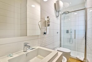 A modern bathroom with a large white bathtub, a toilet, and a glass-enclosed shower area. - Hotel Serenella (Agropoli)