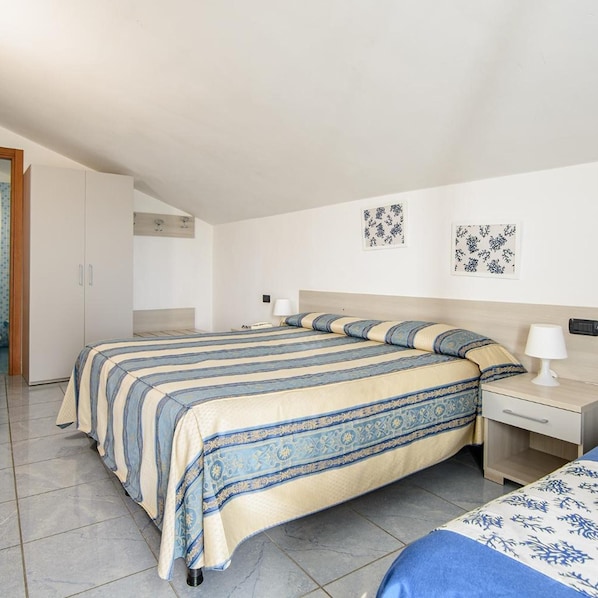 A bedroom with a bed, bedside table, lamp, and wall art.