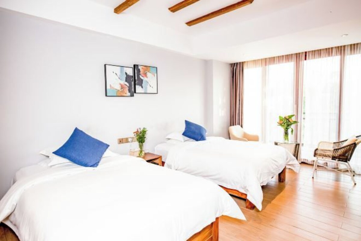 Een hotelkamer met twee bedden, een stoel en een raam met gordijnen.