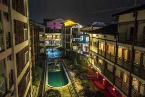 Une cour avec une piscine, entourée d’immeubles à plusieurs étages dotés de balcons et d’un éclairage extérieur.