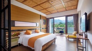 A hotel room with a large bed, a desk, a chair, and a balcony with a view. - Baofeng Homestay (Zhangjiajie National Forest Park) (Zhangjiajie)