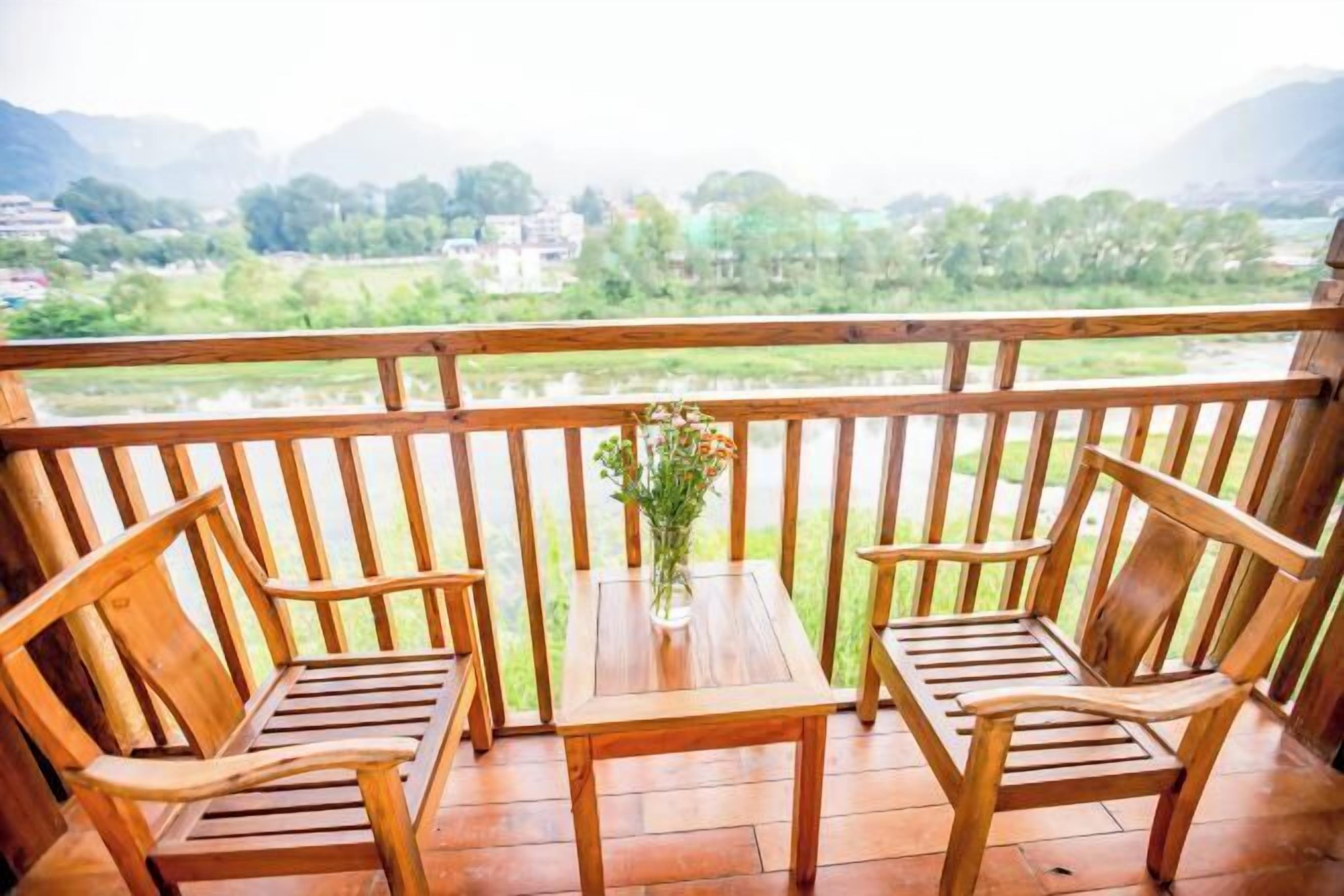 A wooden deck with two chairs and a table, overlooking a river and greenery.