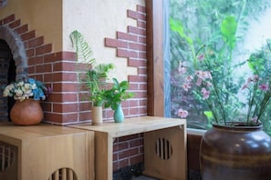 Uma mesa de madeira com plantas em vasos e um muro de tijolos.