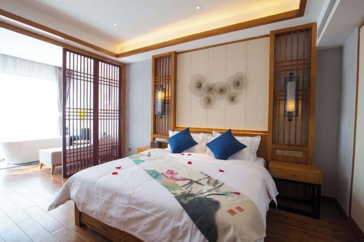 Une chambre avec un grand lit, une tête de lit en bois et une porte coulissante donnant sur une vue agréable.