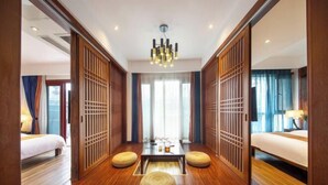 A hotel room with a wooden floor, two beds, a central table, and a decorative partition. - Baofeng Homestay (Zhangjiajie National Forest Park) (Zhangjiajie)