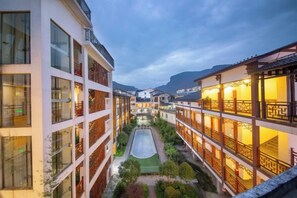 Ein Innenhof mit Gebäuden an beiden Seiten, einem zentralen Weg und Blick auf ferne Berge.