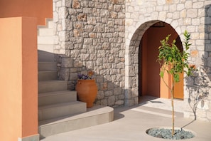 A stone building with a staircase, a large terracotta pot, and a potted plant.
