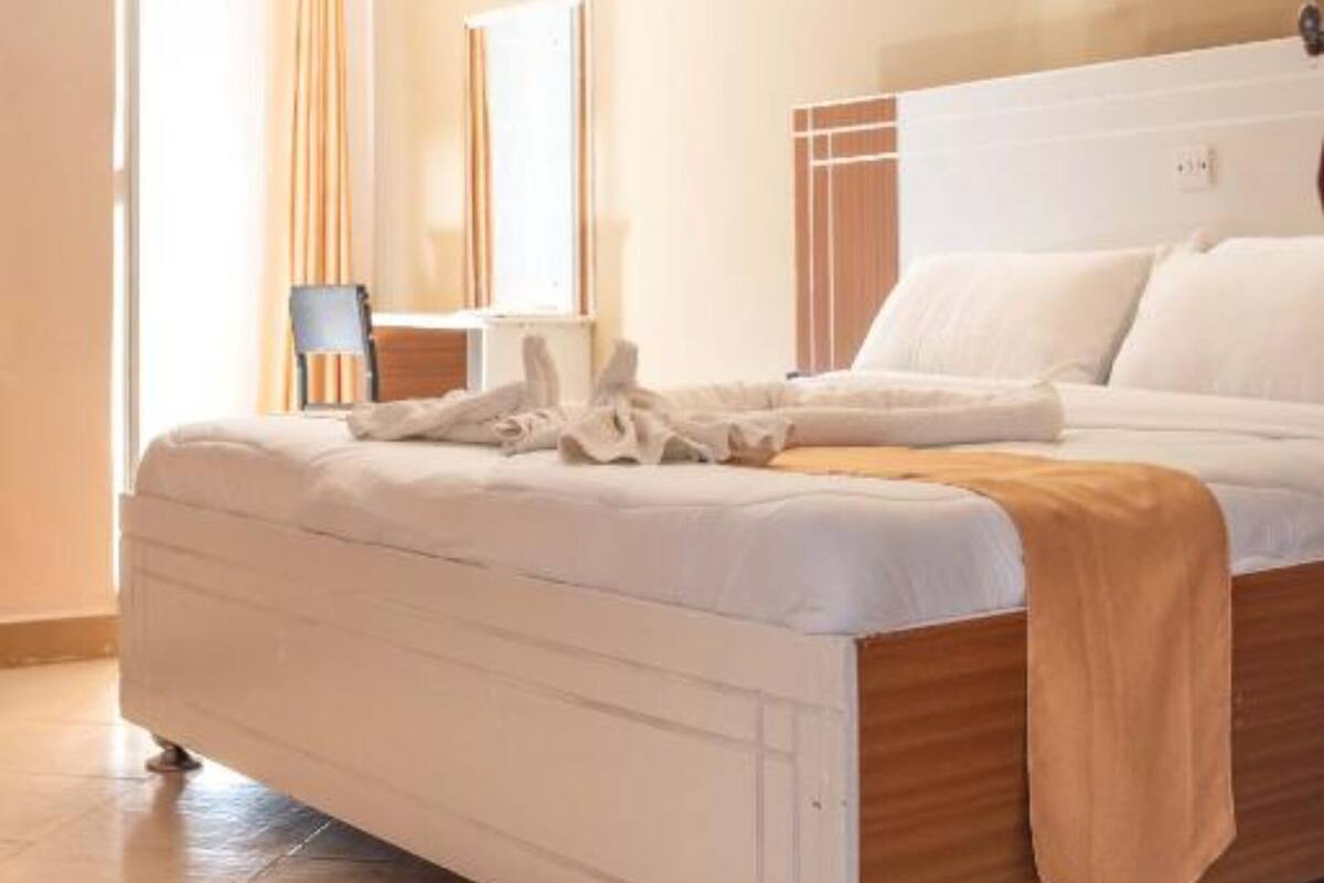 A bedroom with a bed, a chair, a mirror, and a light fixture.