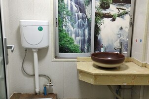 Un baño con inodoro, lavabo y ventana con vistas a una cascada.