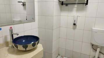 Une salle de bain avec un lavabo en céramique bleue, un miroir, un porte-serviettes et des toilettes.