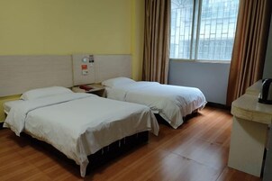 Habitación de hotel con dos camas, un escritorio y una ventana con cortinas.