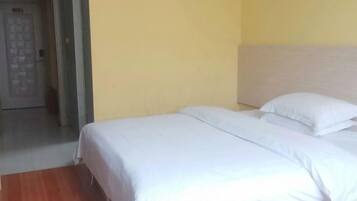 A hotel room with a bed, a wooden floor, and a door.
