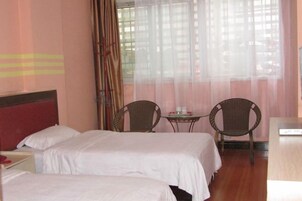 Habitación de hotel con dos camas, una mesita pequeña, dos sillas y un escritorio.