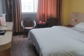 A hotel room with a bed, a desk, a chair, and a window with curtains. - Jinxin Hotel (Hezhou)