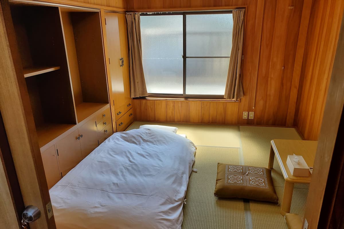 A compact bedroom with a bed, a small table, and a wardrobe.