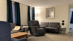 A living room with a grey sofa, a blue armchair, a small table, and a floor lamp.