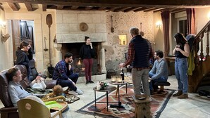 A cozy room with a fireplace, wooden beams, and a group of people gathered around.