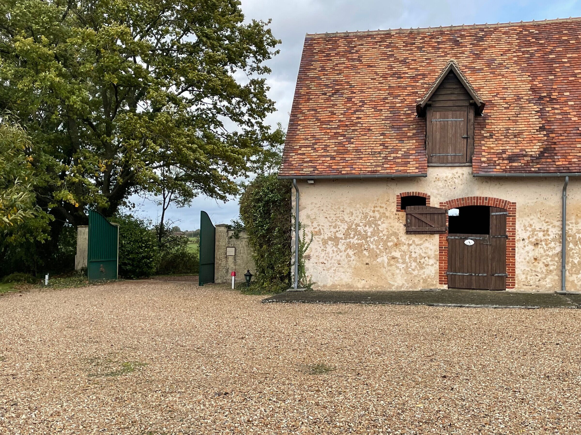 Un bâtiment rustique avec un toit en tuiles, une porte en bois et une petite fenêtre.