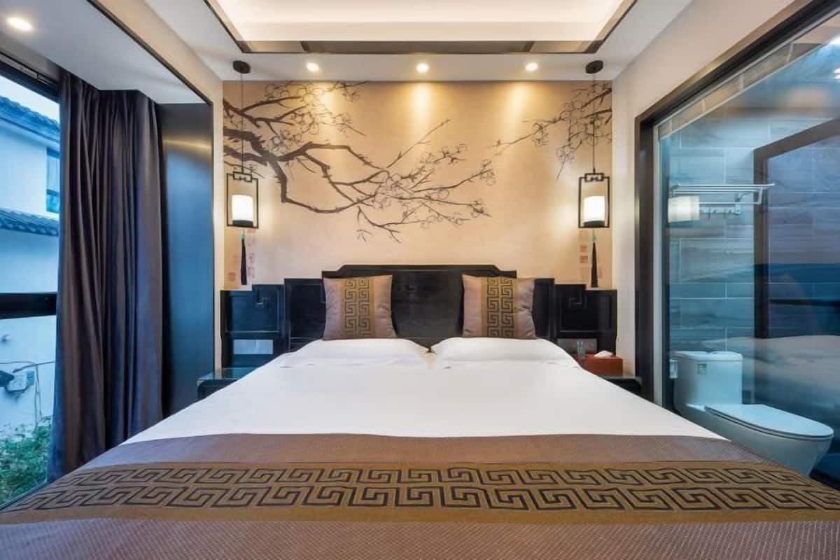 A hotel room with a large bed, a wall-mounted artwork, and a view of the outside.