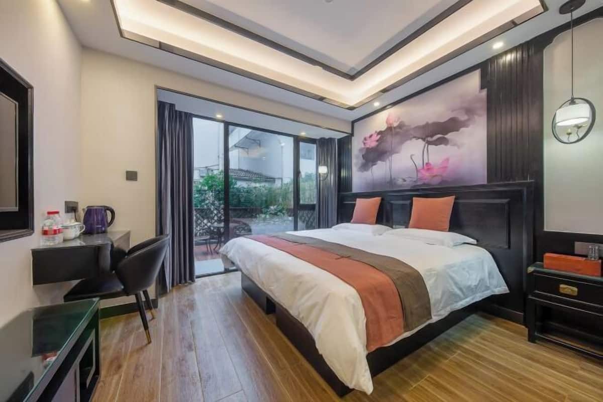 A modern hotel room with a large bed, a desk, and a view of the outdoors.