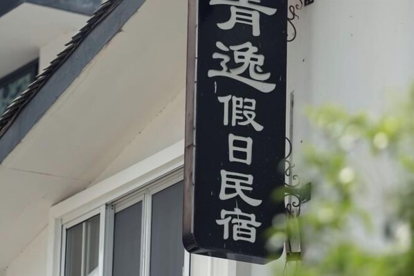 A black sign with white Chinese characters on a building's exterior. - Qingyi Holiday Hostel (Hangzhou)
