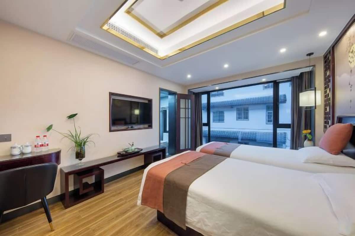 A hotel room with a bed, a desk, a TV, and a window with a view.