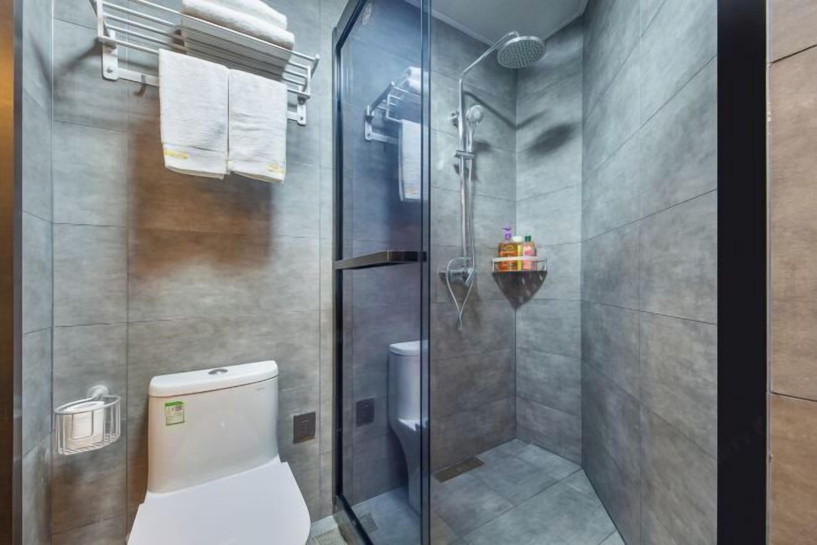 Moderni kylpyhuone, jossa on lasiseinällä varustettu suihku, wc ja pyyhekoukku.