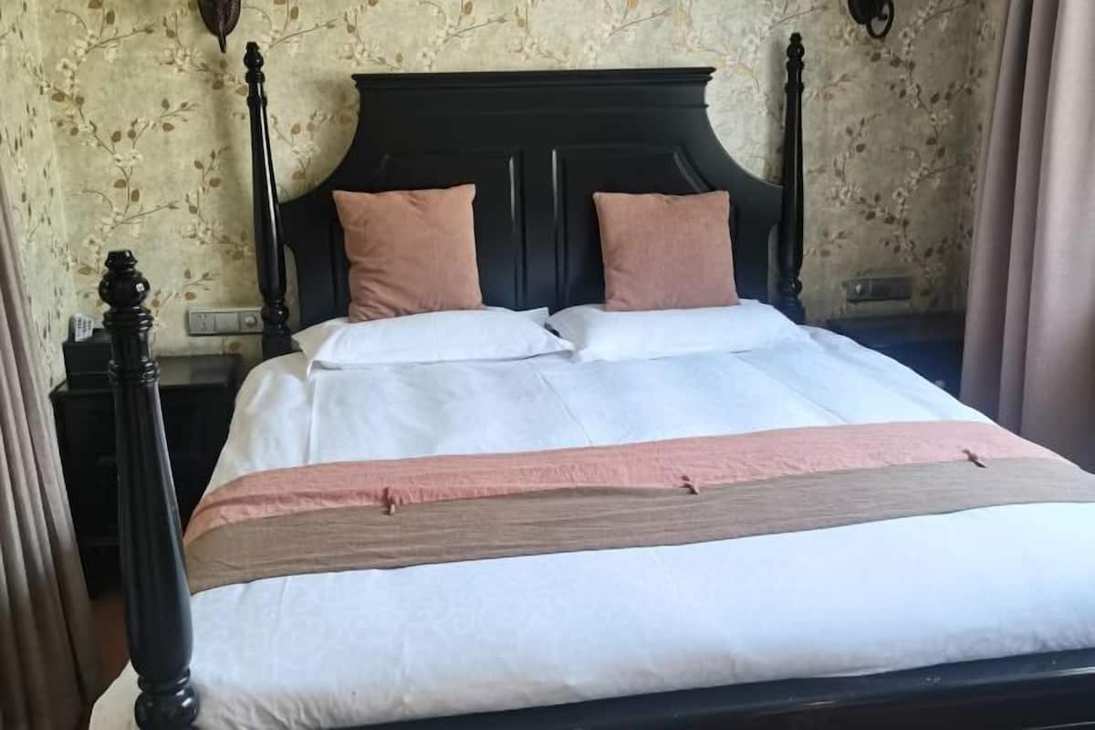A neatly made bed with a wooden headboard, two pillows, and a white and pink bedspread.