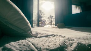 Une chambre d’hôtel faiblement éclairée, avec un lit, un oreiller et un bol posé sur le lit.