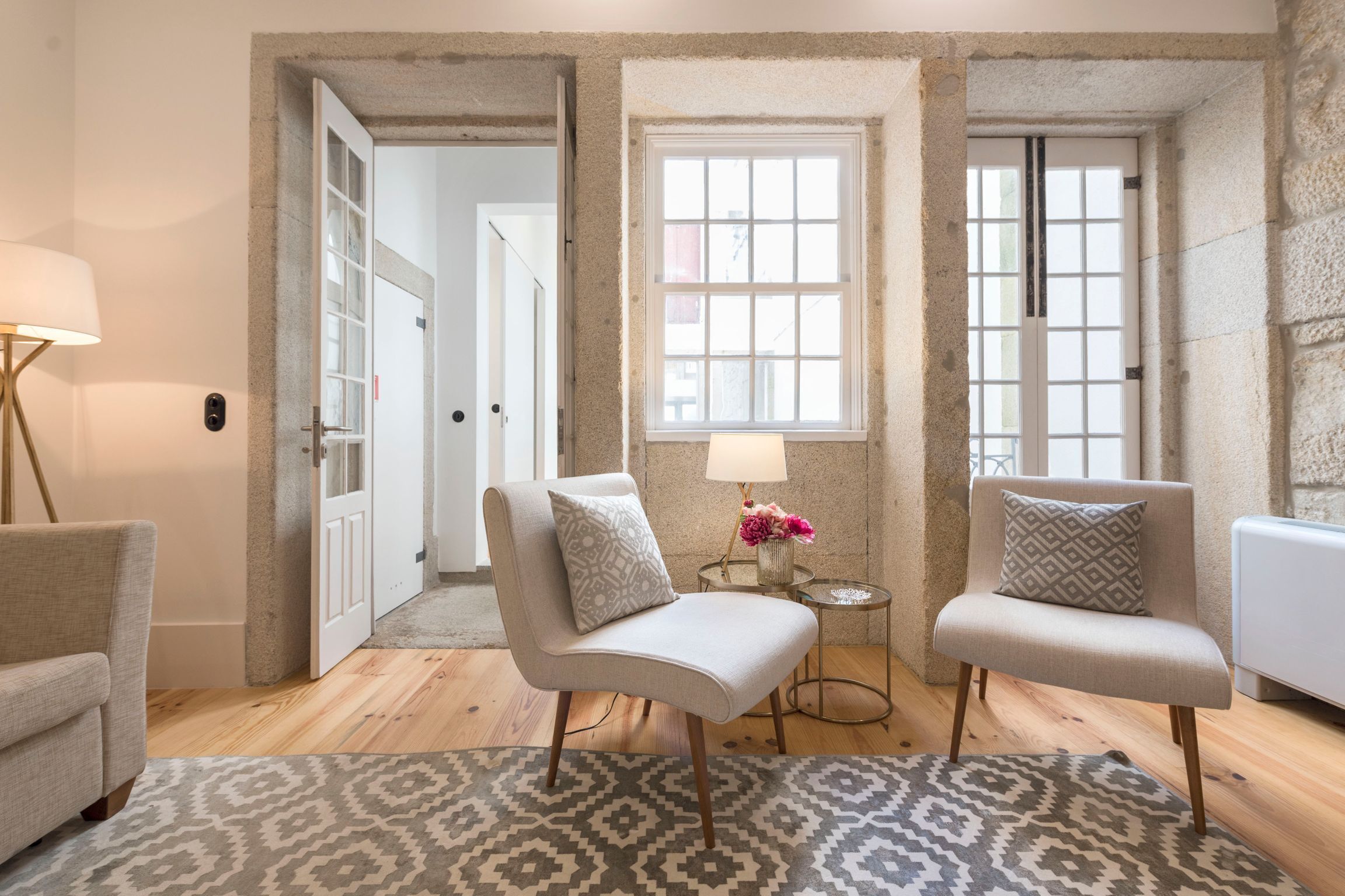 A room with two armchairs, a small table with a lamp, and a patterned rug.