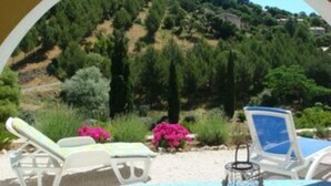 A view through a circular window of a hillside with a pool area featuring two lounge chairs and a table. - Well-kept apartment domaine with, pools, tennis. Pet friendly (Roquebrune-sur-Argens)