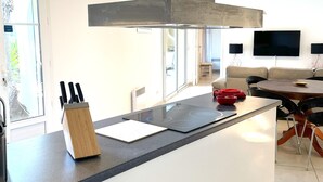 A modern kitchen with a central island, a built-in stove, and a stainless steel range hood. - Well-kept apartment domaine with, pools, tennis. Pet friendly (Roquebrune-sur-Argens)