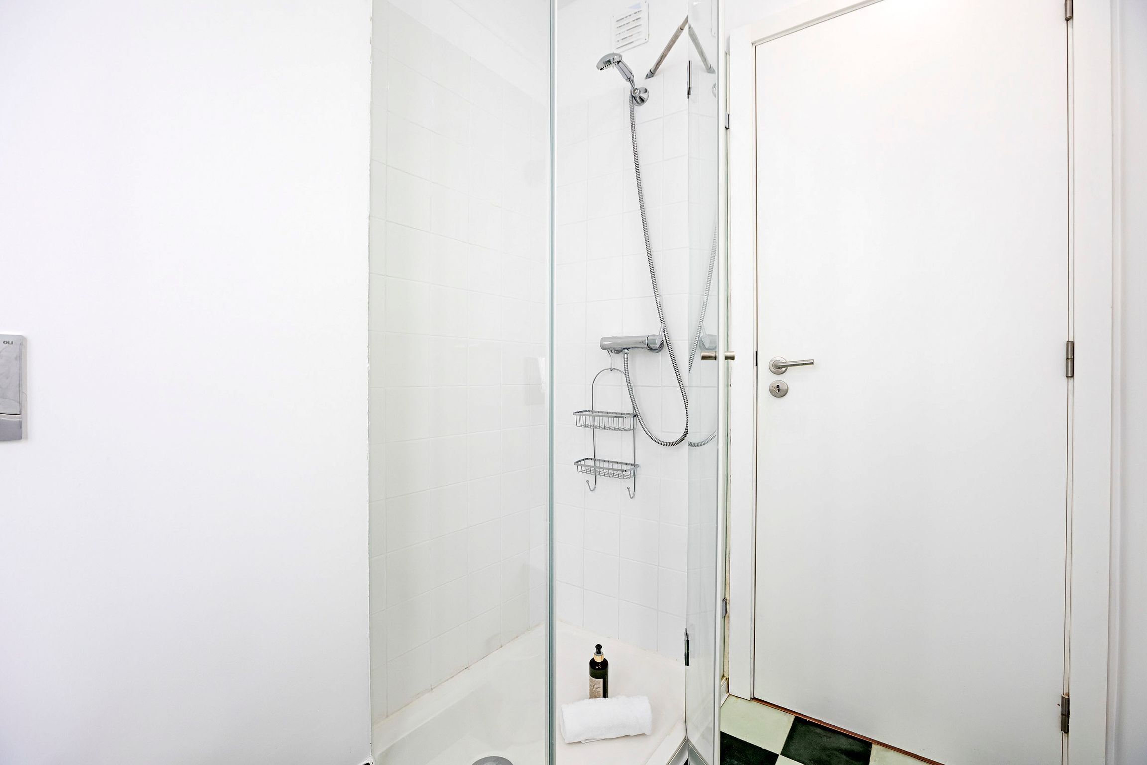 Ein modernes Badezimmer mit Duschkabine aus Glas, einer weißen Toilette und einem kleinen Handtuchhalter.