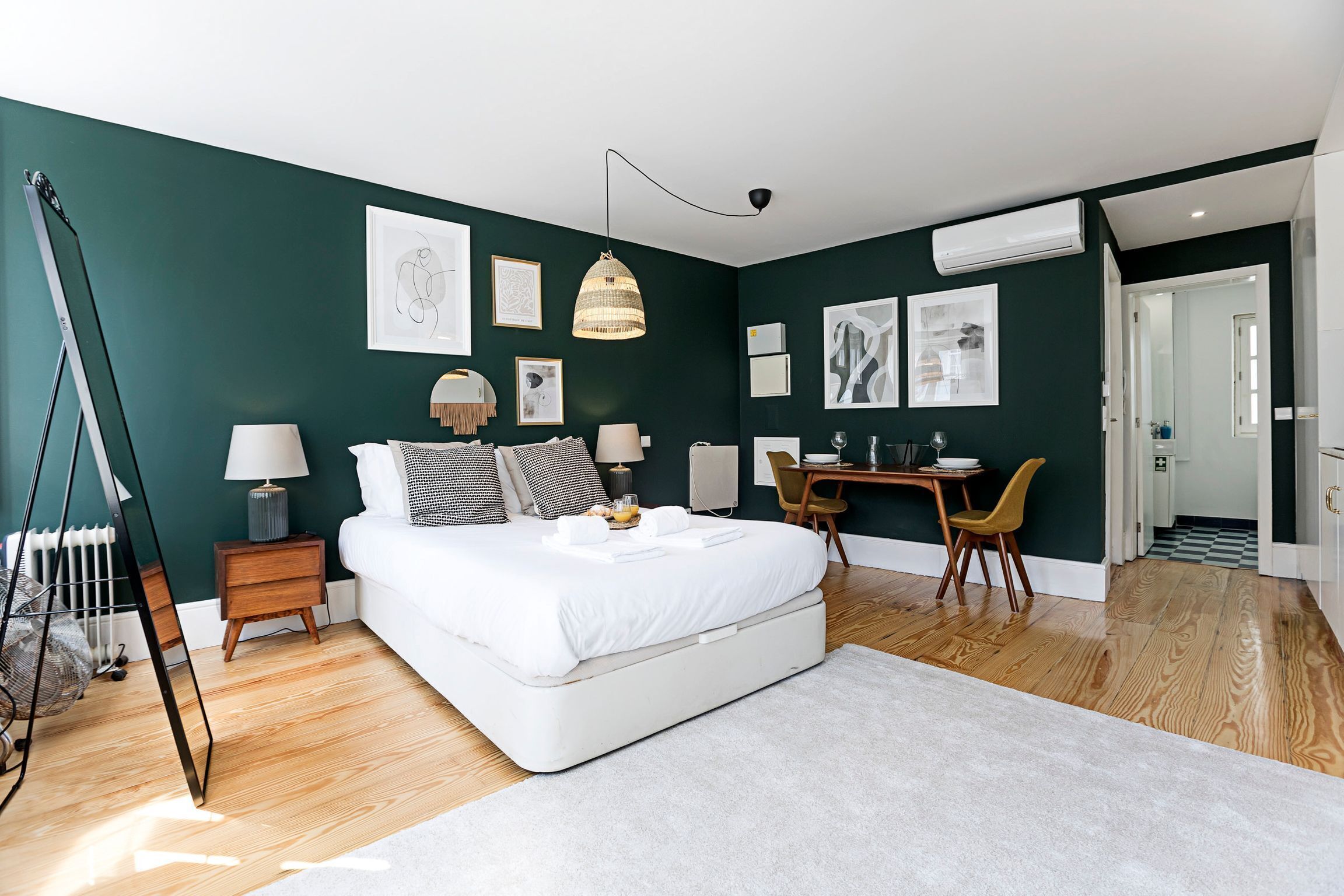 A modern bedroom with a large bed, bedside tables, a desk, and chairs.