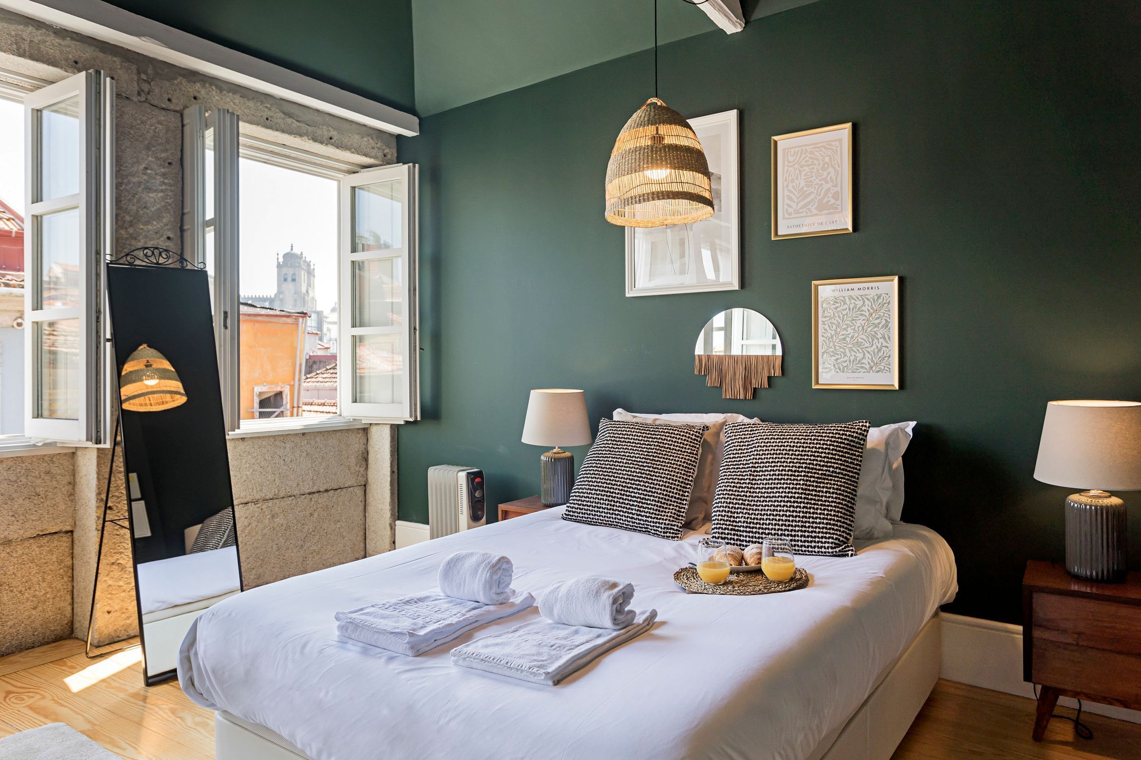 A neatly made bed with towels, a bedside table with a lamp, and framed artwork on the wall.