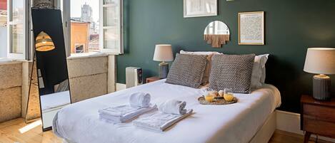 A neatly made bed with towels, a bedside table with a lamp, and framed artwork on the wall.