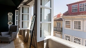 A room with a large window, a chair, and a painting on a stand. - Lóios 66 by LovelyStay (Porto)