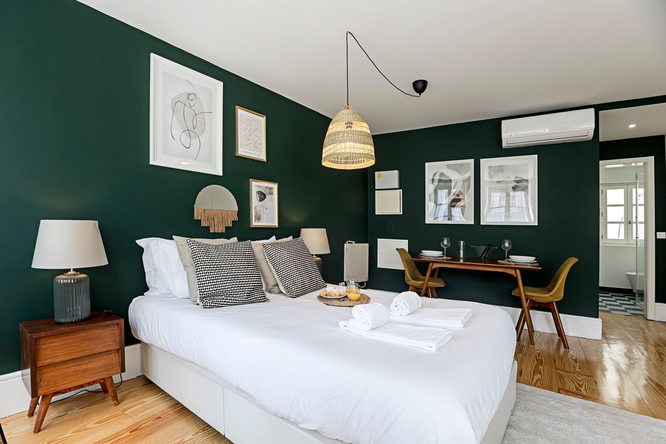 Un dormitorio moderno con una cama grande, mesitas de noche, un escritorio y sillas.