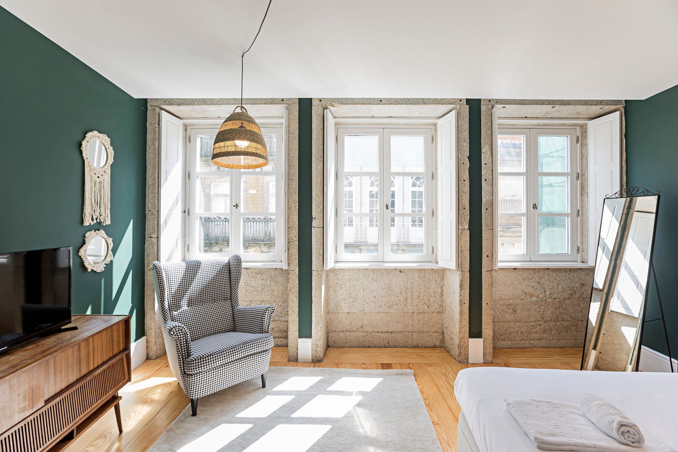 A bedroom with a bed, a television, a chair, and a large window.