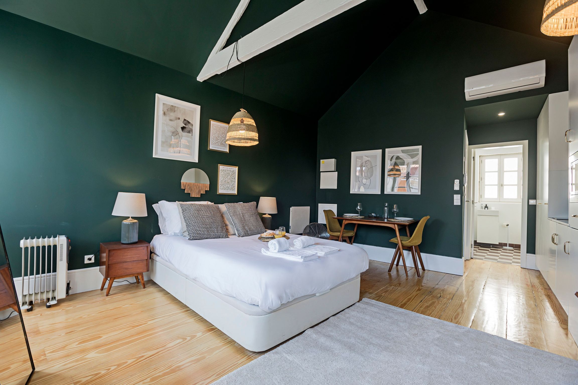 Un dormitorio moderno con una cama grande, mesitas de noche, un escritorio y una silla.