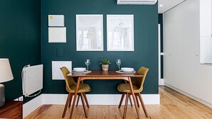 A dining area with a wooden table, two chairs, and a potted plant. - Lóios 66 by LovelyStay (Porto)