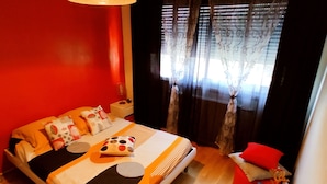 A modern bedroom with a large bed, a bedside table, a lamp, and a window with curtains. - Ideally located 70m2 T3 apartment with private balcony and secure parking (Saint-Priest)
