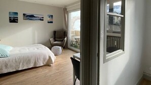 Un dormitorio con cama, una silla, una mesa y un balcón con vistas.