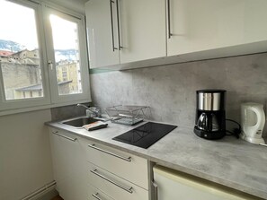 Una cucina con lavello, scolapiatti, macchina del caffè e pensili.