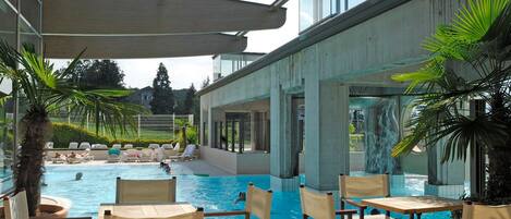 Un espace piscine avec des chaises et une zone abritée.