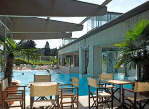 Zona de piscina con sillas de descanso y un área de estar techada.