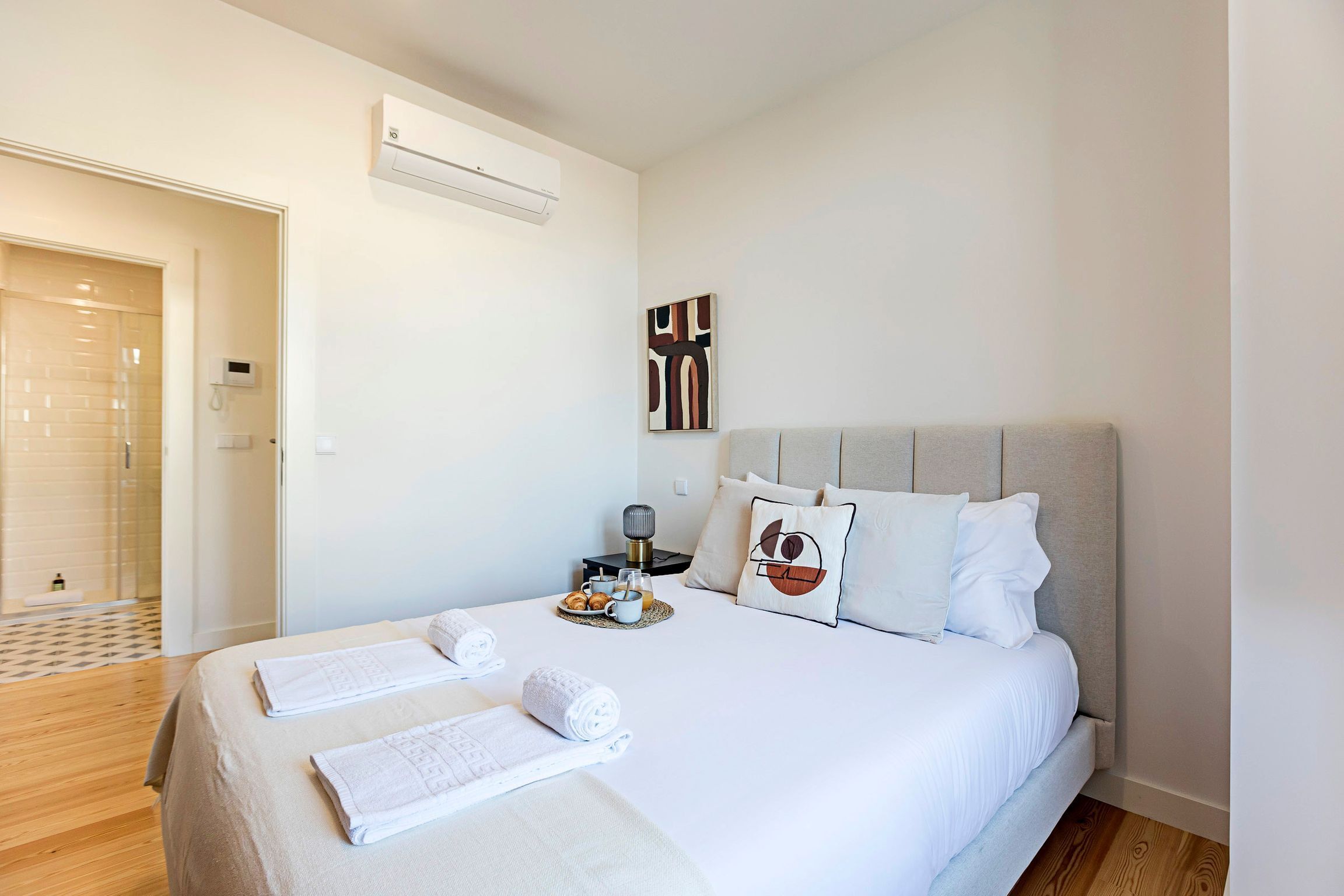 Une chambre d’hôtel équipée d’un lit, de serviettes, d’une table de chevet avec une lampe et d’un climatiseur fixé au mur.