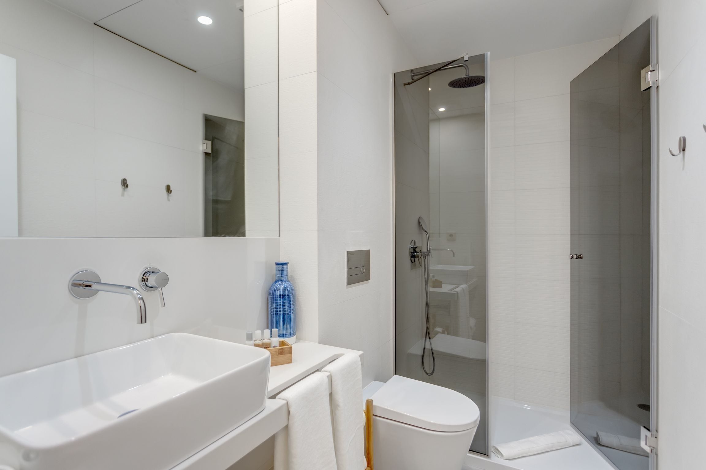 A modern bathroom with a large white sink, a toilet, and a glass-enclosed shower.