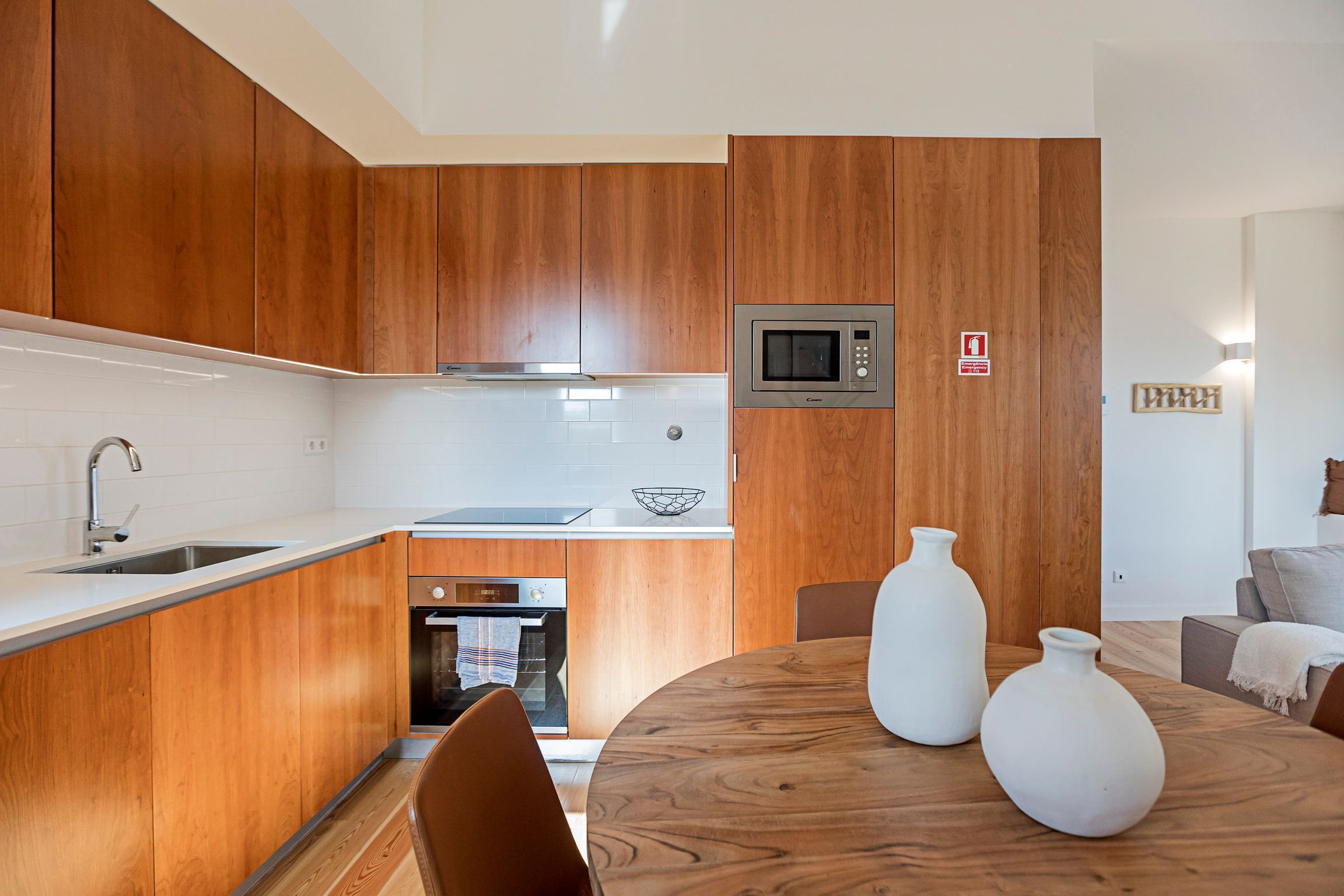 A modern kitchen with wooden cabinets, a microwave, and a dining area with a wooden table and chairs.